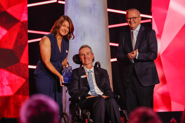 Neale Daniher receives the Australian of the Year award in January 2025, flanked by his wife Jan and the Prime Minister, Anthony Albanese.